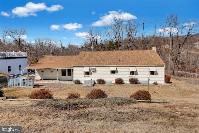 rear view of property featuring a shingled roof, a chimney, and a patio