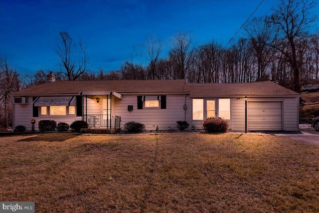 single story home featuring a chimney, an attached garage, an AC wall unit, driveway, and a front lawn