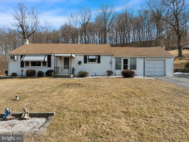 ranch-style home with a garage, driveway, a front yard, and a wall unit AC