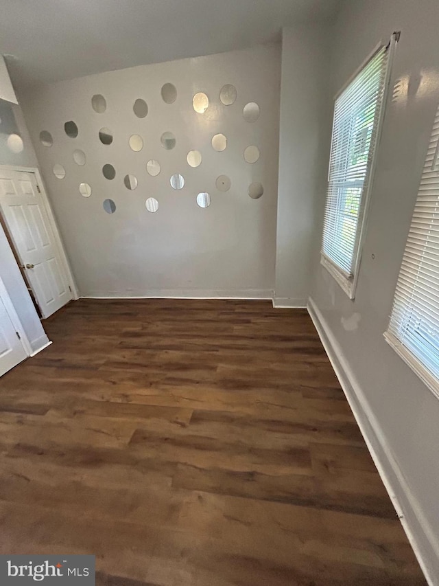 spare room featuring baseboards and dark wood finished floors