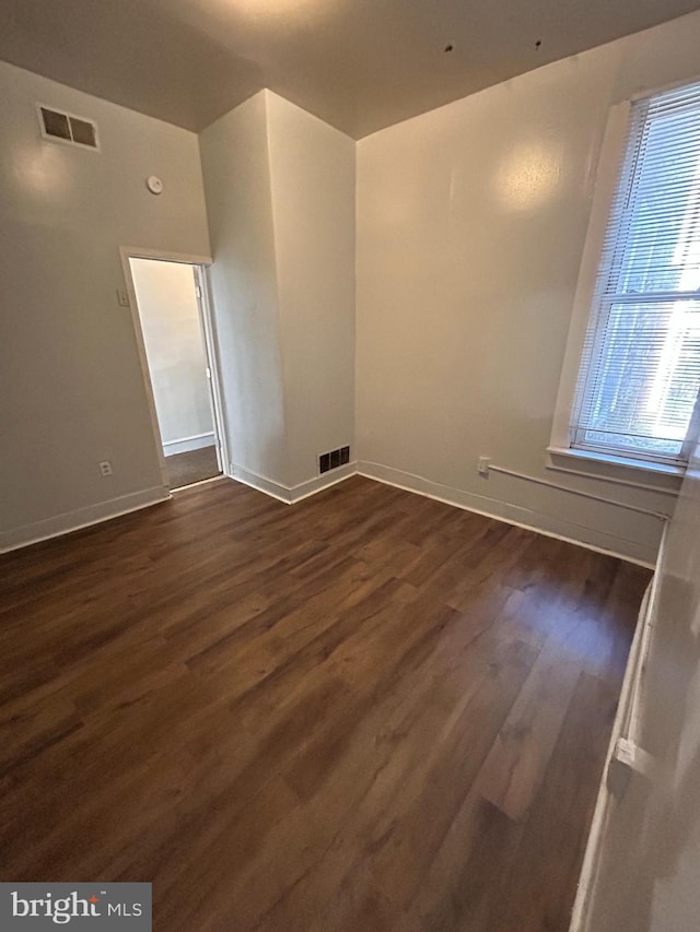 spare room with dark wood-style floors, baseboards, and visible vents