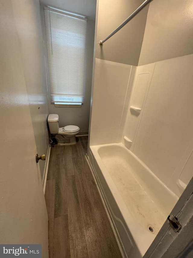 bathroom featuring toilet, baseboards, wood finished floors, and shower / bathtub combination