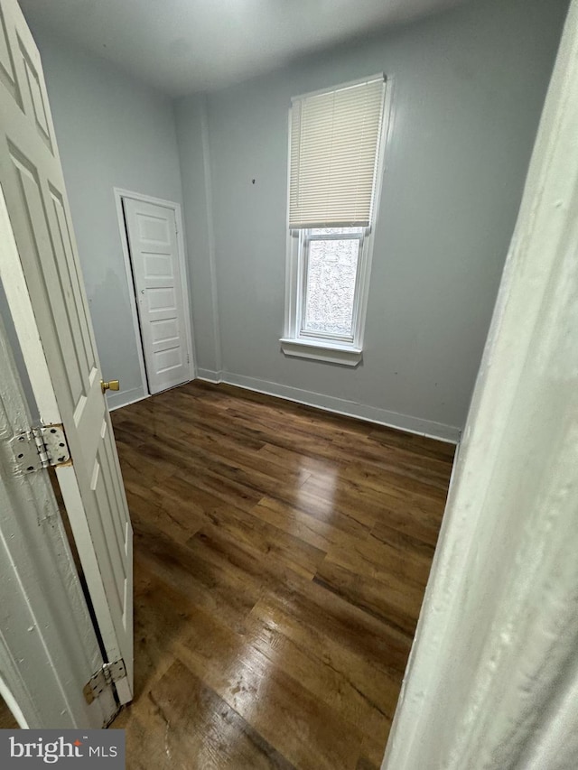 unfurnished bedroom with dark wood finished floors and baseboards