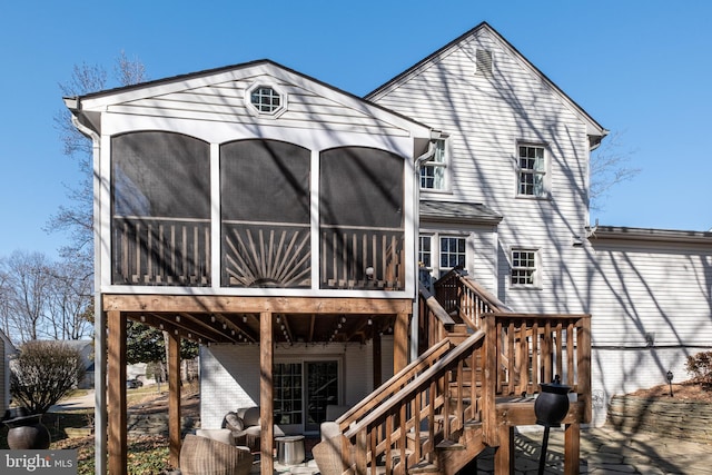 rear view of property with a sunroom, stairs, and a deck