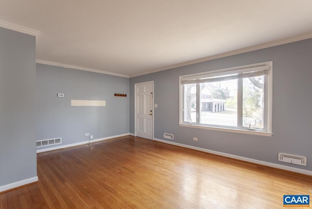 spare room with visible vents, baseboards, wood finished floors, and ornamental molding