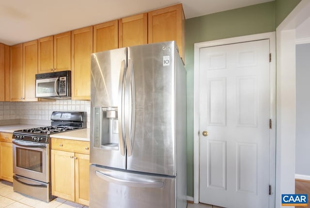 kitchen with stainless steel appliances, light brown cabinetry, light countertops, and tasteful backsplash