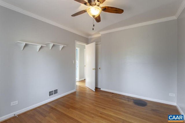 unfurnished room featuring visible vents, ornamental molding, ceiling fan, wood finished floors, and baseboards