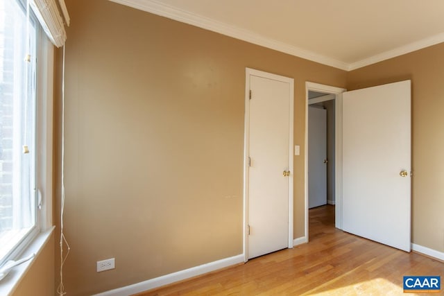 unfurnished bedroom featuring baseboards, light wood-style floors, and crown molding