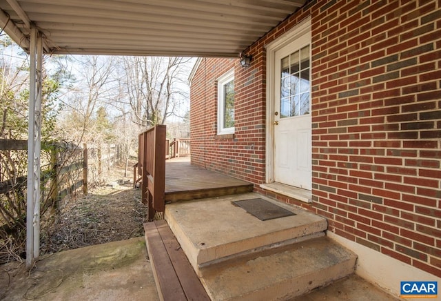 view of exterior entry with brick siding and fence