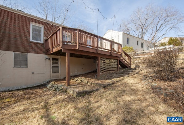 rear view of house with stairs, a deck, and brick siding