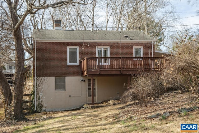 back of house featuring roof with shingles, a chimney, a deck, and brick siding