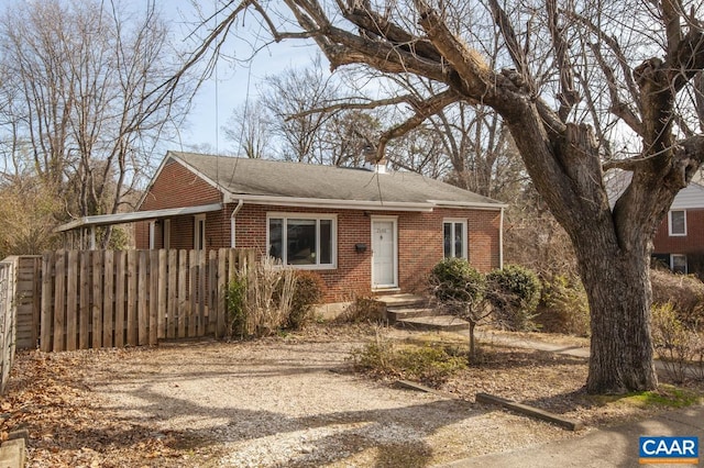 view of front of house featuring dirt driveway, fence, and brick siding