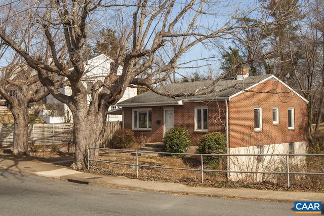 view of front of house with a fenced front yard, brick siding, and a chimney