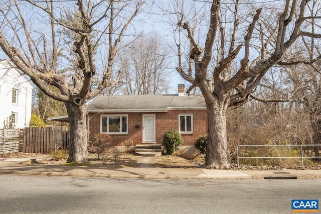 single story home with brick siding, a chimney, and fence