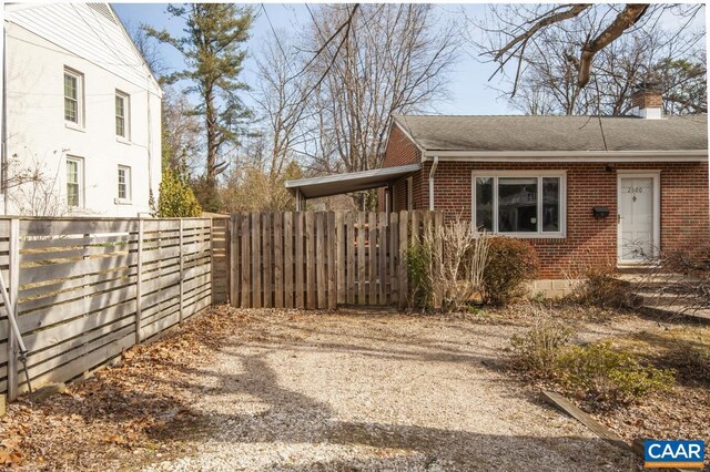 view of home's exterior featuring brick siding, a chimney, a shingled roof, and fence