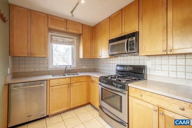 kitchen featuring stainless steel appliances, light countertops, a sink, and decorative backsplash