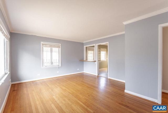 unfurnished room featuring crown molding, plenty of natural light, wood finished floors, and baseboards