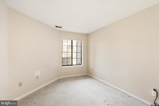 carpeted empty room featuring baseboards, visible vents, and a textured ceiling