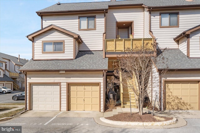 townhome / multi-family property featuring a garage, roof with shingles, and a balcony