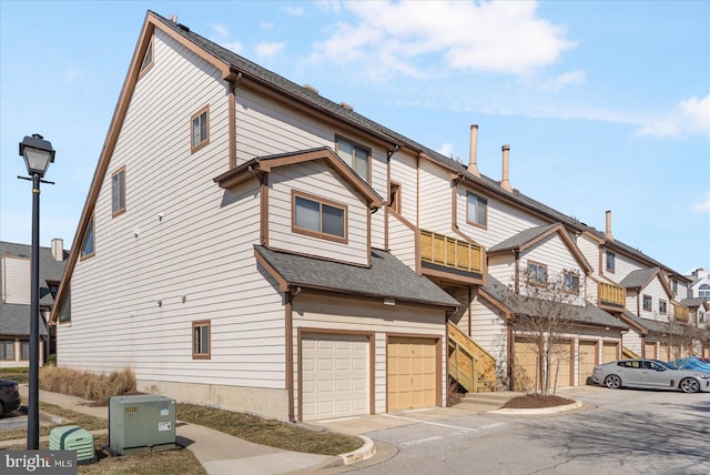 townhome / multi-family property with a garage, roof with shingles, and a residential view