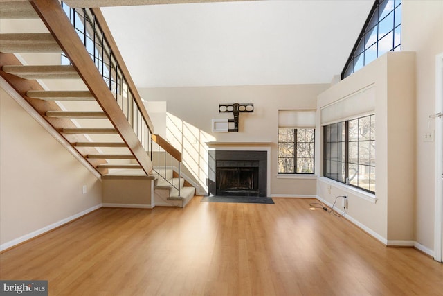 unfurnished living room featuring high vaulted ceiling, baseboards, and wood finished floors