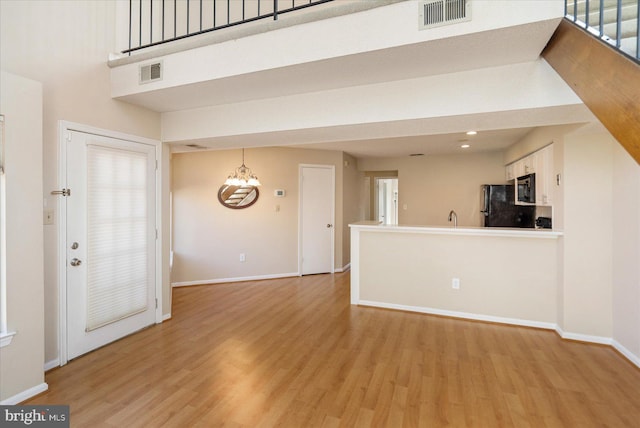 unfurnished living room with light wood-style floors, visible vents, and baseboards