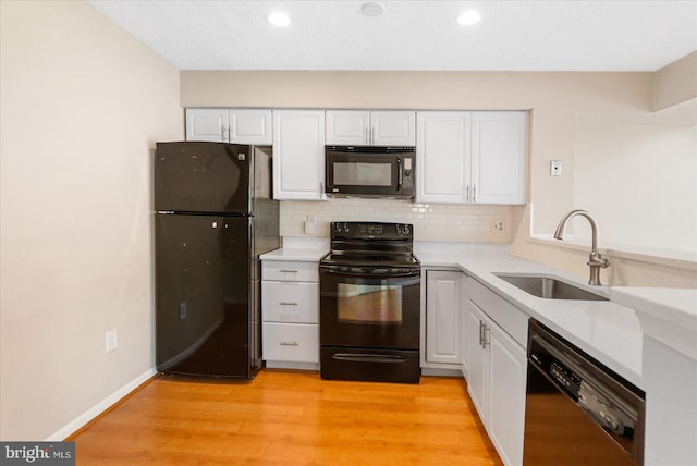 kitchen with black appliances, backsplash, a sink, and white cabinetry