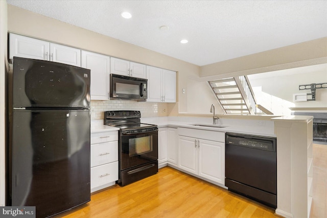 kitchen with white cabinets, a sink, and black appliances