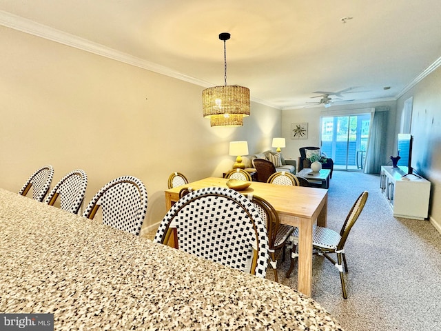 carpeted dining room with ceiling fan, baseboards, and crown molding