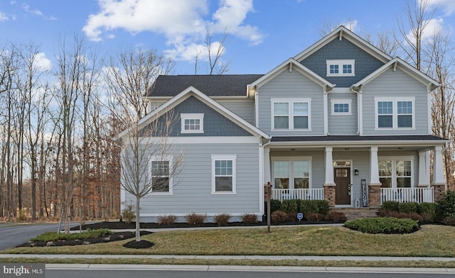 craftsman-style house with covered porch, a front lawn, and aphalt driveway