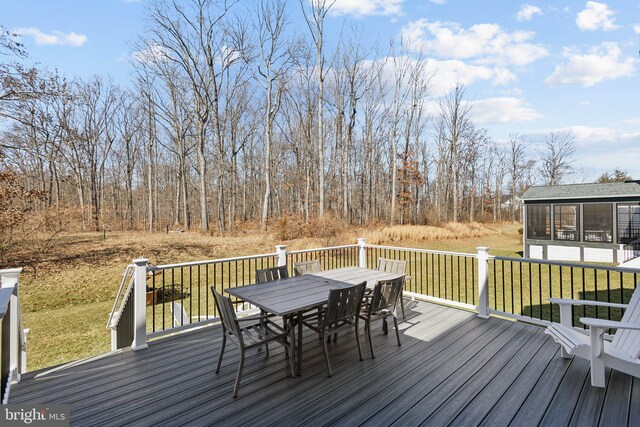 deck featuring a sunroom, outdoor dining area, and a yard