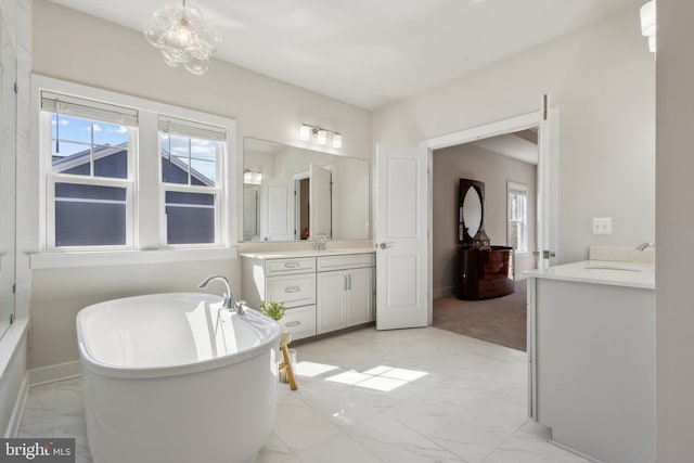 full bathroom with marble finish floor, a soaking tub, vanity, and baseboards