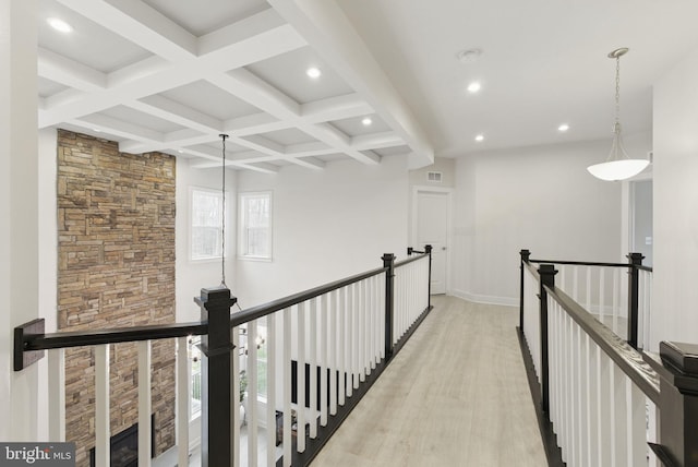 hall with coffered ceiling, visible vents, an upstairs landing, light wood-style floors, and beam ceiling