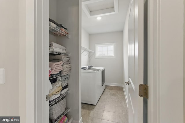 clothes washing area with light tile patterned floors, attic access, washing machine and dryer, laundry area, and baseboards