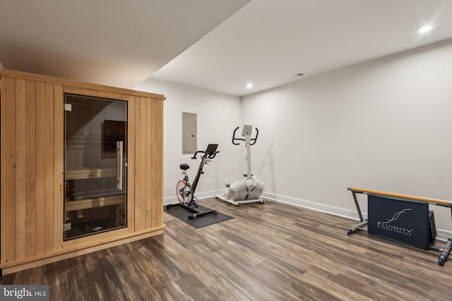 exercise area featuring recessed lighting, wood finished floors, electric panel, and baseboards