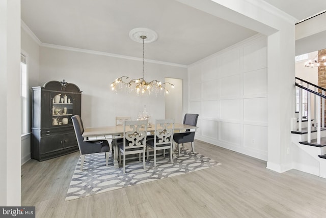 dining area featuring stairs, a decorative wall, crown molding, and a notable chandelier