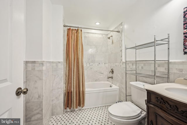 bathroom featuring toilet, a wainscoted wall, vanity, tile walls, and shower / bath combo with shower curtain