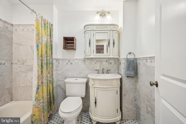 full bathroom featuring toilet, shower / tub combo, vanity, tile walls, and wainscoting