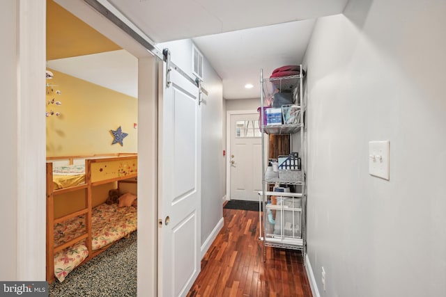 hall featuring dark wood-style floors, a barn door, baseboards, and recessed lighting