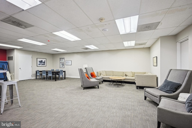 living area with baseboards, visible vents, a drop ceiling, and carpet flooring