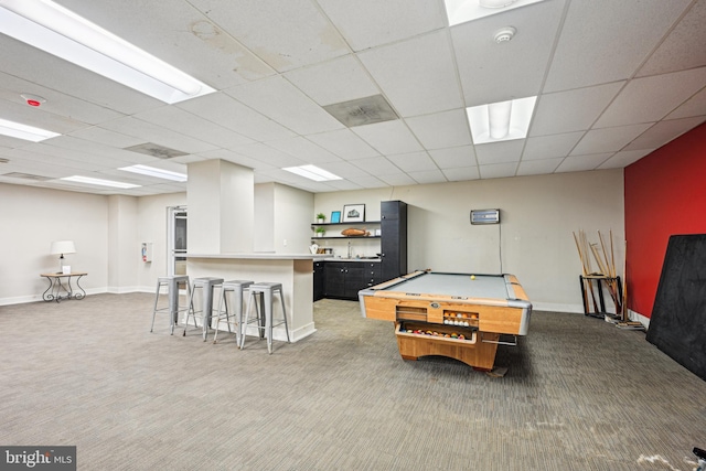 recreation room featuring carpet floors, a drop ceiling, and baseboards