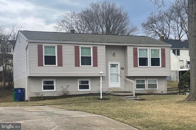 bi-level home with a front lawn and a chimney