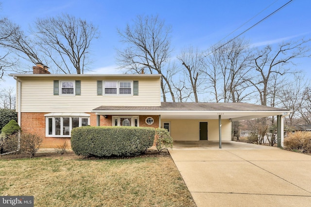 traditional-style home featuring brick siding, an attached carport, a front lawn, a chimney, and driveway