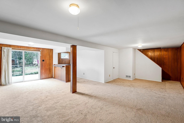 basement featuring visible vents, carpet floors, and wood walls