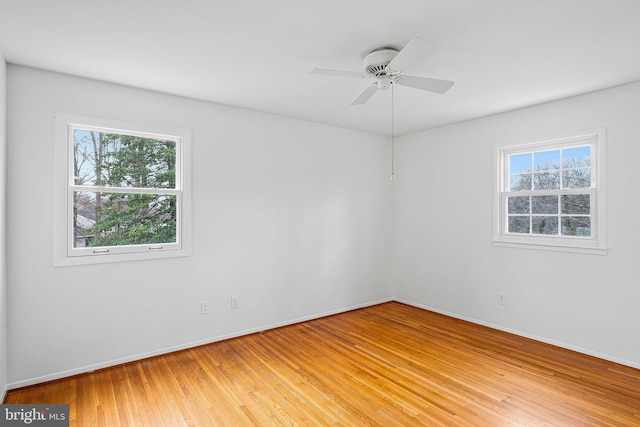 spare room featuring light wood finished floors, ceiling fan, and baseboards