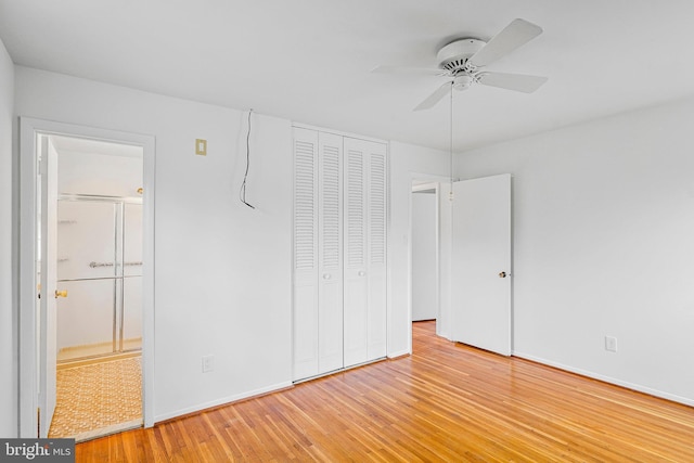 unfurnished bedroom featuring a closet, baseboards, ensuite bath, and light wood-style flooring