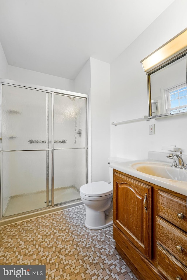 bathroom featuring toilet, vanity, and a shower stall