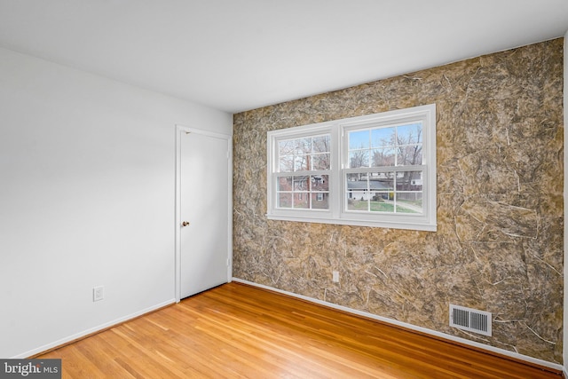 unfurnished room featuring visible vents, baseboards, and wood finished floors