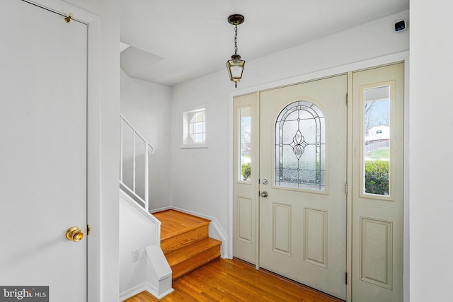 entrance foyer featuring a healthy amount of sunlight, wood finished floors, and stairs