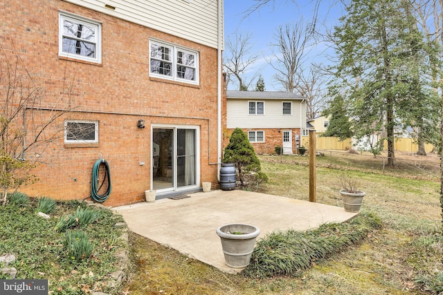 back of property with fence, a patio area, brick siding, and a lawn